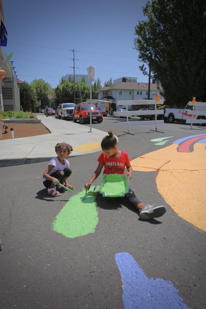 Kids with Color Outside the Lines help paint an intersection mural in Lloyd