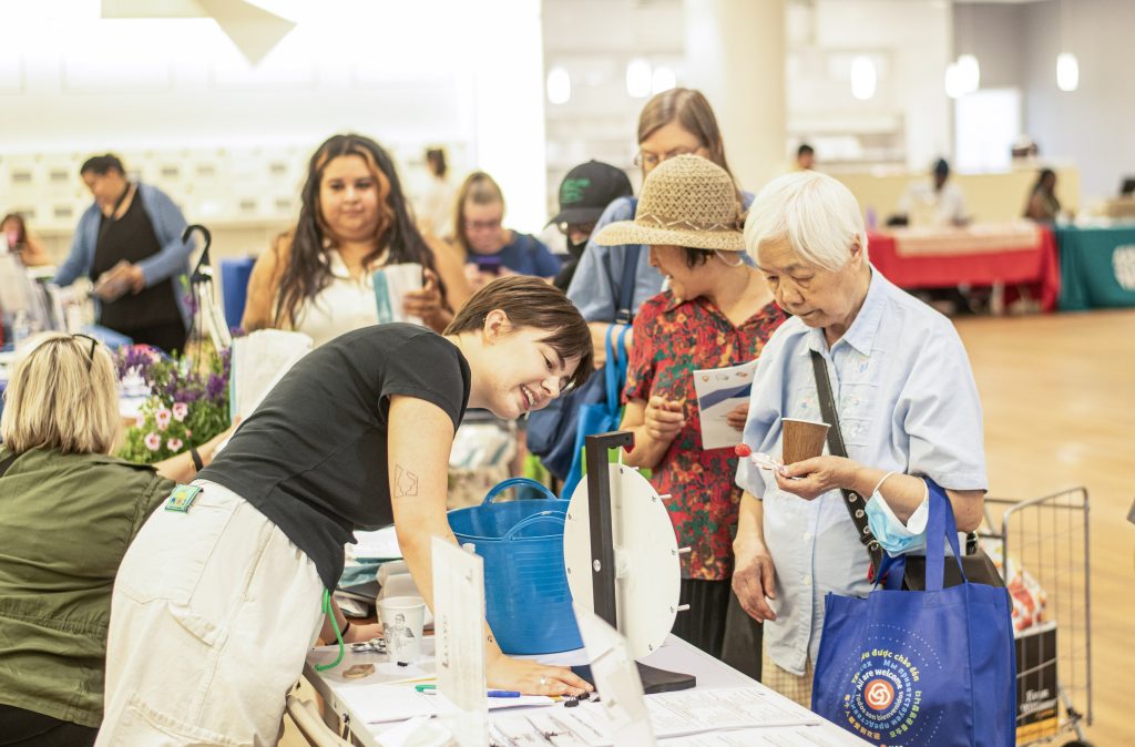 photo of the 2023 Lloyd Resource Fair showing a lloyd ecodistrict staff member sharing resources with adults